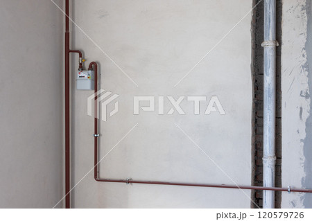 Gas counter with gas pipes in a corner of new unfinished apartment or house. 120579726