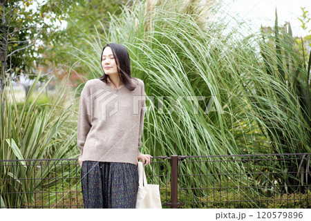 植物を背景に立つ女性 120579896