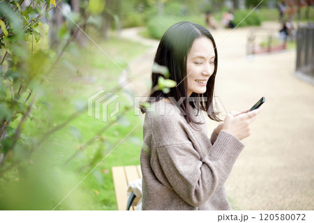 公園のベンチでスマホを見る女性 公園のベンチでスマホを見る女性 120580072