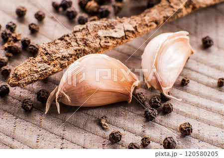 garlic on wooden surface.White garlic bulbs and peeled garlic in ceramic bowl on rough green old wooden background. 120580205