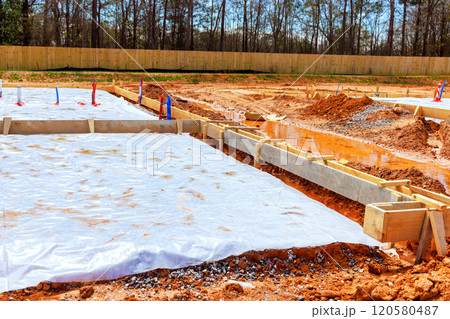 Groundwork is underway at residential construction site, featuring wooden frames protective covering spread across foundation. 120580487