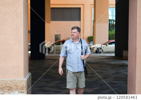 Man in blue shirt and shorts on a city street on a summer day Man in blue shirt and shorts on a city street on a summer day 120581461