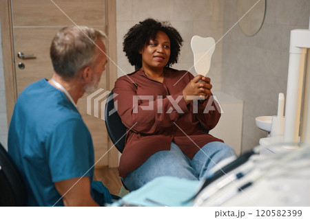 Smiling Patient Holding Mirror during Dental Checkup Smiling Patient Holding Mirror during Dental Checkup 120582399