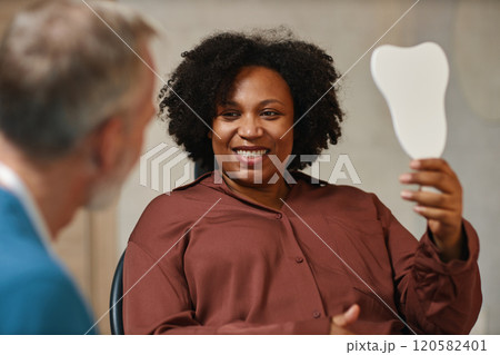 Smiling African American Woman Holding Mirror During Meeting Smiling African American Woman Holding Mirror During Meeting 120582401