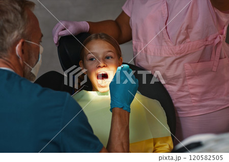 Examining Young Girl's Teeth During Dental Checkup 120582505