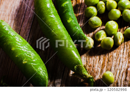 Pods of green peas and pea on a dark wooden surface, top view.Ripe pods of green peas on a wooden surface. Green peas are visible from the open pods. Panorama. Pods of green peas and pea on a dark wooden surface, top view.Ripe pods of green peas on a wooden surface. Green peas are visible from the open pods. Panorama. 120582998
