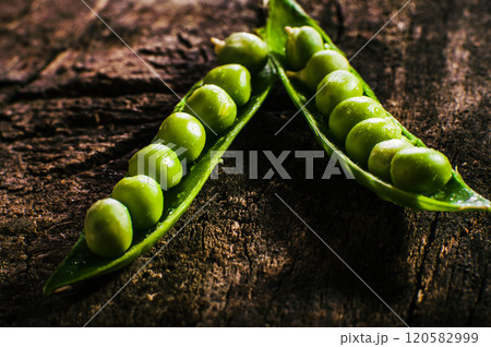 Pods of green peas and pea on a dark wooden surface, top view.Ripe pods of green peas on a wooden surface. Green peas are visible from the open pods. Panorama. Pods of green peas and pea on a dark wooden surface, top view.Ripe pods of green peas on a wooden surface. Green peas are visible from the open pods. Panorama. 120582999