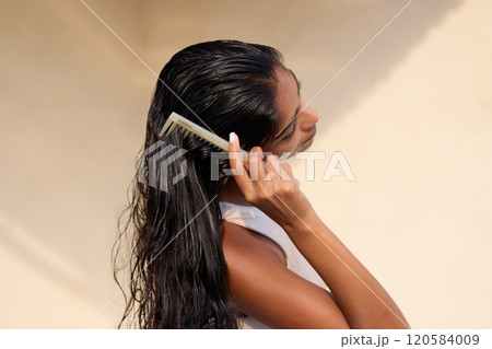 Woman Combing Long Wet Hair in Natural Sunlight Setting 120584009