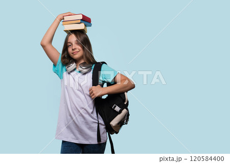 Girl balancing books on head, wearing backpack and headphones Girl balancing books on head, wearing backpack and headphones 120584400