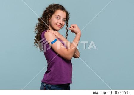 Girl flexing arm with blue bandage after receiving vaccine shot Girl flexing arm with blue bandage after receiving vaccine shot 120584595