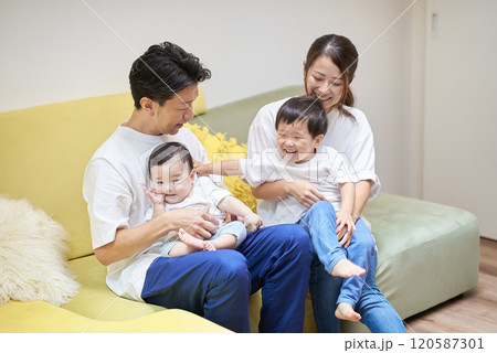 部屋のソファーでくつろぐ親子4人 120587301