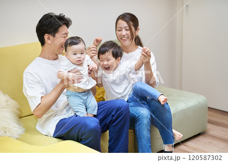 部屋のソファーでくつろぐ親子4人 120587302