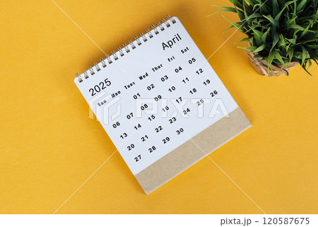 April 2025 desk calendar on yellow background. Directly above. Flat lay April 2025 desk calendar on yellow background. Directly above. Flat lay 120587675