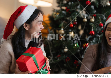 Joyful Young Couple Celebrating Christmas with Gifts and Laughter by the Christmas Tree Joyful Young Couple Celebrating Christmas with Gifts and Laughter by the Christmas Tree 120588174