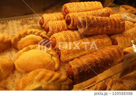 Pastries are laid out in the window of the cafe of the store close-up: sausages in dough and baked pies 120588386
