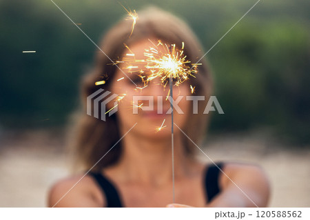 Beautiful woman with sparklers on the beach 120588562