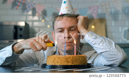 A solitary man enjoys a bittersweet birthday moment, lighting candles on a cake while reflecting on the passing years 120588773