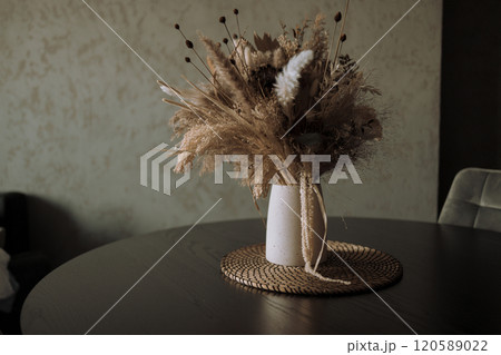 Stylish modern dried flower arrangement in a cream vase at home room. Composition with many different dried flowers in vases, on a light background. 120589022