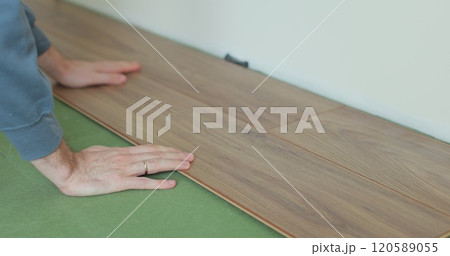 Man lays laminate flooring on the floor in a room. Repair of the floor of the house. 120589055