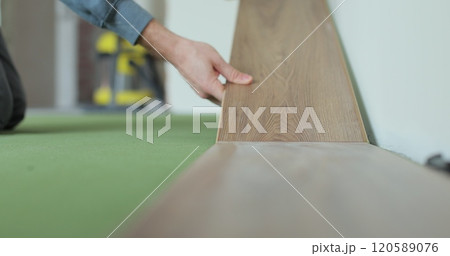 Worker, lays laminate on a green backing. Technology and process. Repair of the floor of the house. 120589076