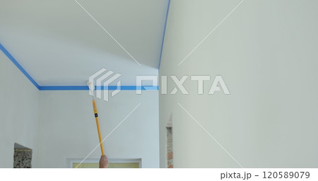Painting the ceiling with a long stick with a roller. Home repairs and finishing works. Painting the ceiling with a long stick with a roller. Home repairs and finishing works. 120589079