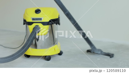 Man vacuums the floor with an industrial vacuum cleaner. Preparing the floor for laying laminate. Man vacuums the floor with an industrial vacuum cleaner. Preparing the floor for laying laminate. 120589110