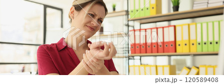 Tired woman employee kneads wrist and feels pain in office 120589408