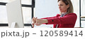 Lady manager stretches arms before starting work on computer 120589414