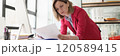 Concentrated blonde woman reads documents leaning on table 120589415