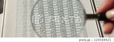 Hand of woman holds magnifier glass over accounting document 120589421