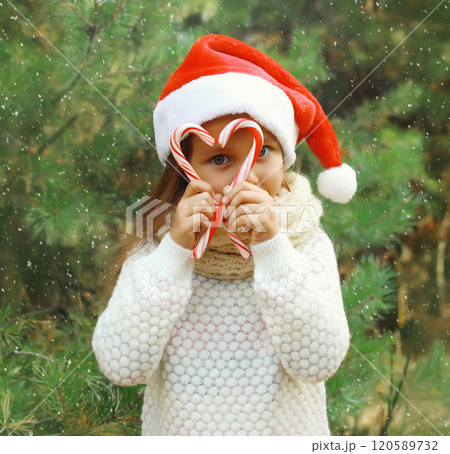 Christmas portrait of happy smiling little girl child in santa red hat with sweet lollipop cane toys 120589732