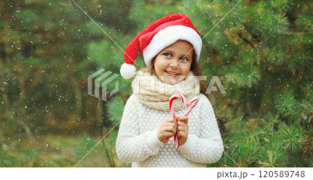 Christmas portrait of happy smiling little girl child in santa red hat with sweet lollipop cane toys 120589748
