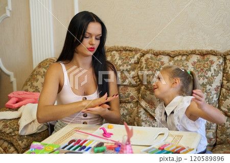 Mother and daughter enjoying craft activities together in a cozy living room 120589896