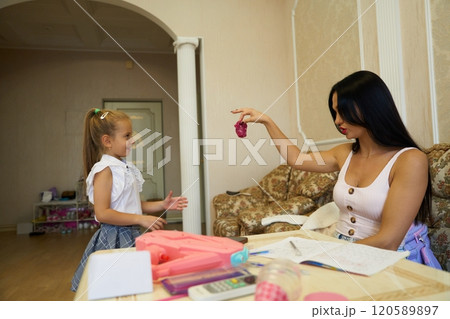 Woman and young girl playing together in a cozy living room in summer 120589897