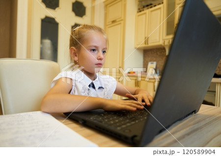 Young girl focused on her homework at a kitchen table during the afternoon Young girl focused on her homework at a kitchen table during the afternoon 120589904