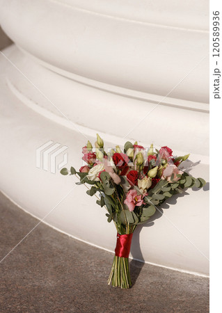 A bouquet of flowers is sitting on the ground next to a white pillar 120589936