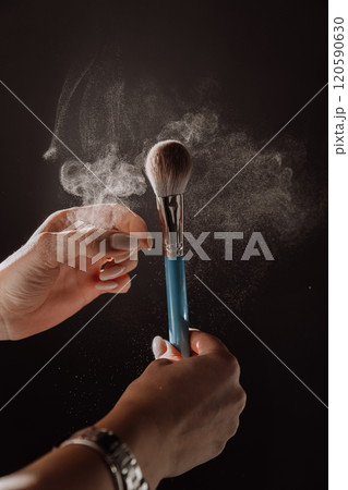 Makeup brush in action with powder particles floating in dramatic lighting, beauty in motion Makeup brush in action with powder particles floating in dramatic lighting, beauty in motion 120590630