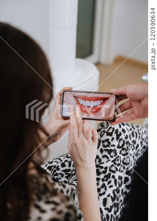 Patient reviewing smile transformation on smartphone at dental clinic consultation 120590634