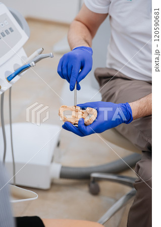 Dentist demonstrating dental model procedure with precision tools in a modern clinic setting Dentist demonstrating dental model procedure with precision tools in a modern clinic setting 120590681