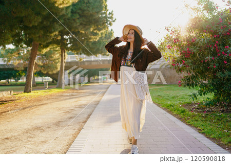 A Stylish Woman in a Chic Outfit Enjoys a Peaceful Walk in Beautiful Nature at Golden Hour A Stylish Woman in a Chic Outfit Enjoys a Peaceful Walk in Beautiful Nature at Golden Hour 120590818