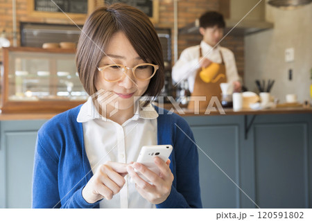 カフェでスマホを操作する女性 カフェでスマホを操作する女性 120591802