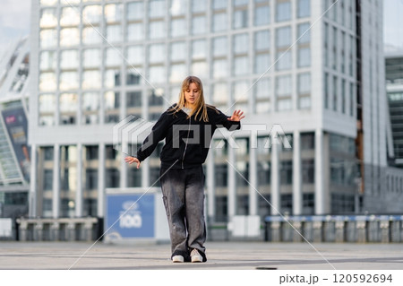 Young dancer performs on an urban plaza during a sunny afternoon in the city 120592694