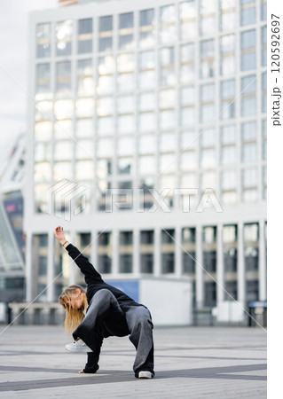Dancer performing dynamic move in urban setting during evening light Dancer performing dynamic move in urban setting during evening light 120592697