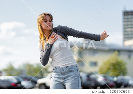 Young woman dancing joyfully in an urban parking lot under clear sky 120592698