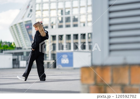 Young woman walking in urban area on a sunny day showcasing modern architecture 120592702