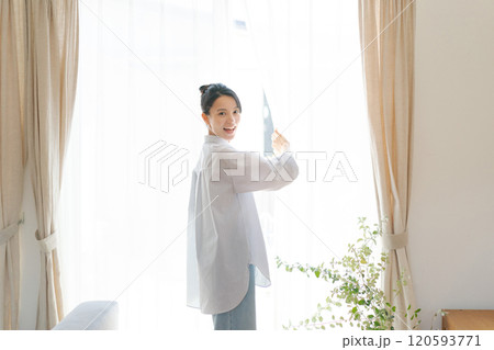 リビングの窓際に立つ笑顔の女性 120593771