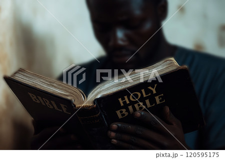 African American man holds an open black holy Bible in his hands. 120595175
