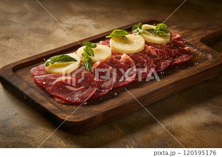 Fresh raw beef slices on a plate set on a dark wooden table. 120595176