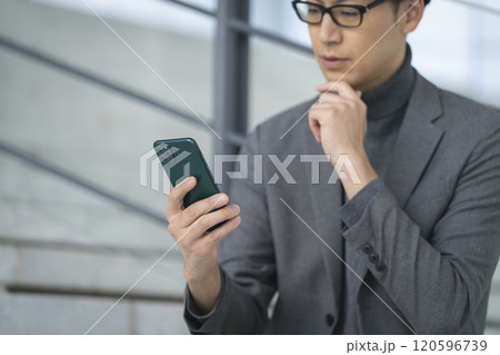 スマートフォンを持ったミドルの男性の手元 120596739