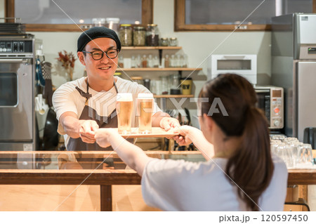 ビールを出す飲食店・居酒屋のスタッフ・店員の男性と受け取るホールスタッフの女性 120597450